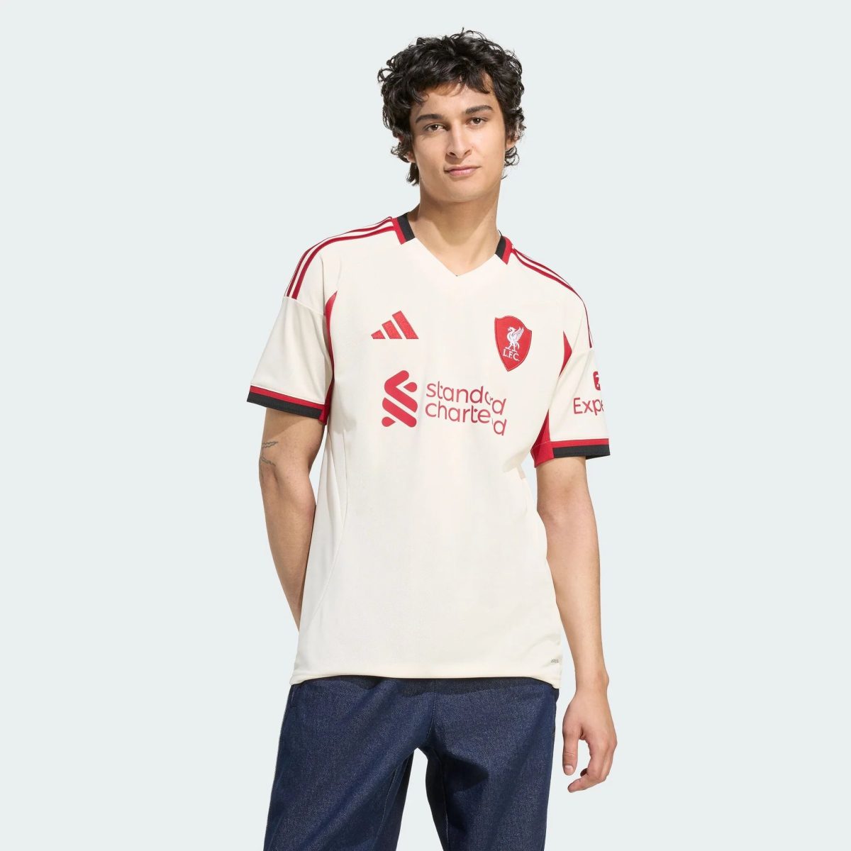 Young man in a white Liverpool FC jersey with red trim, posing against a pale background.