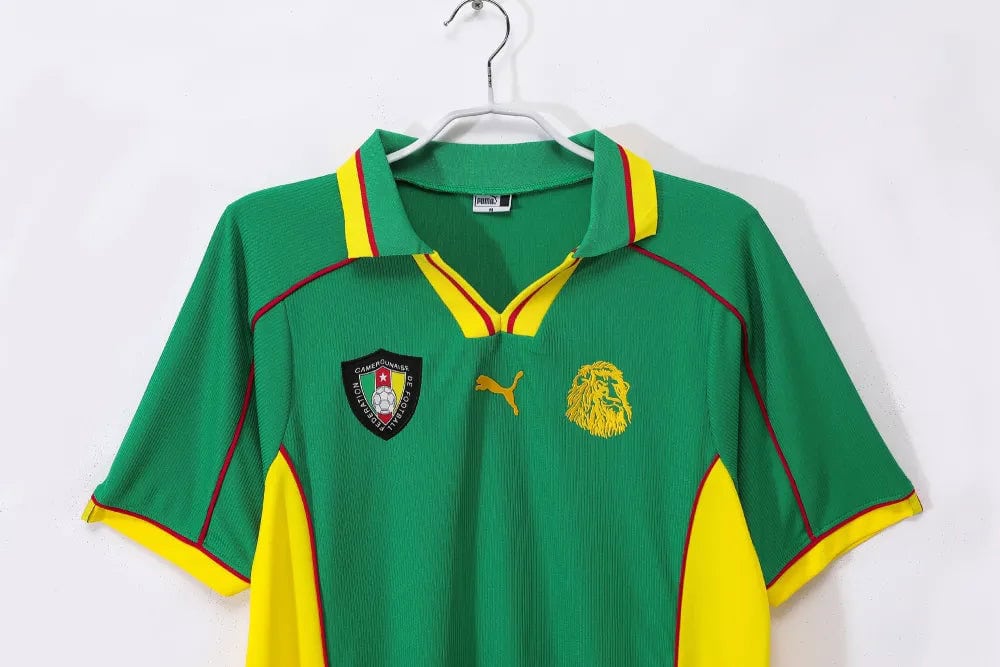 rn-image_picker_lib_temp_cb4f78cb-e3c3-4303-bd34-c5016a3d07ad | UAE SPORT STORE Green Cameroon national team football jersey on a hanger, with red and yellow trim and sponsor PUMA logo on the chest side. Approachable, informative.