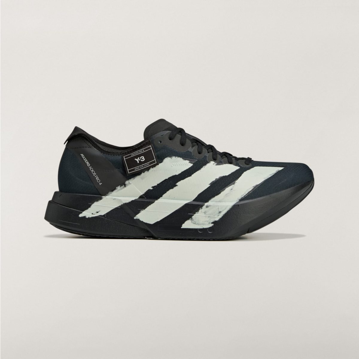 Close-up of a black Adidas sneaker with white stripes on a pale background, showing the toe and laces area.