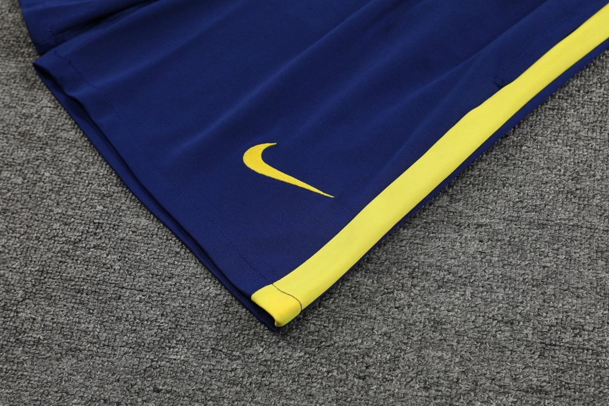 Blue athletic pants with a yellow stripe and Nike swoosh on a gray carpeted surface in the background.