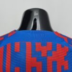 Close-up of a glossy black helmet on blue and red patterned fabric against a light background.