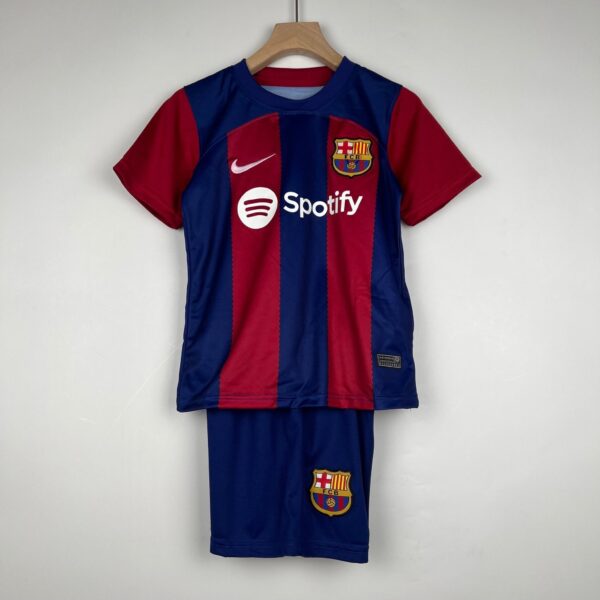 Blue and red FC Barcelona jersey hanging on a wooden hanger, featuring the club crest and Spotify sponsor logo on the front.