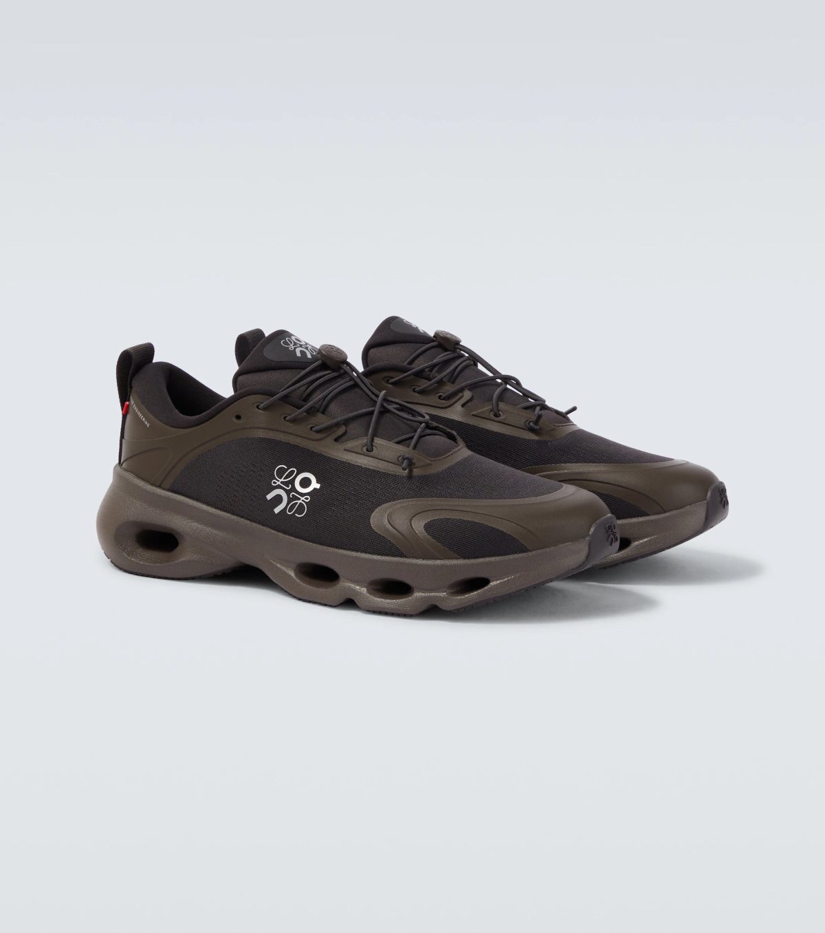 Brown hiking shoe pair shown from a low angle with rugged sole and laces, against a light gray background.