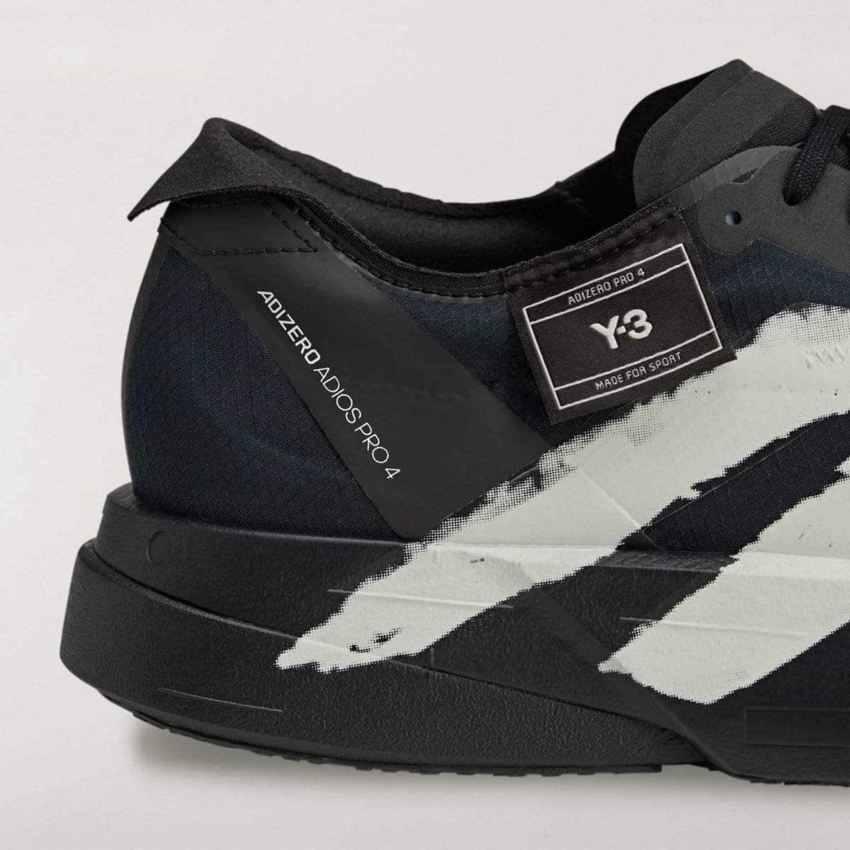Close-up of a black sneaker showing a textured upper, stitched details, and a Velcro strap with a label reading Y-3 Adidas Pro 4.
