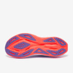 Orange running shoe sole with purple tread pattern and cutouts on a light background, showing traction design for grip.