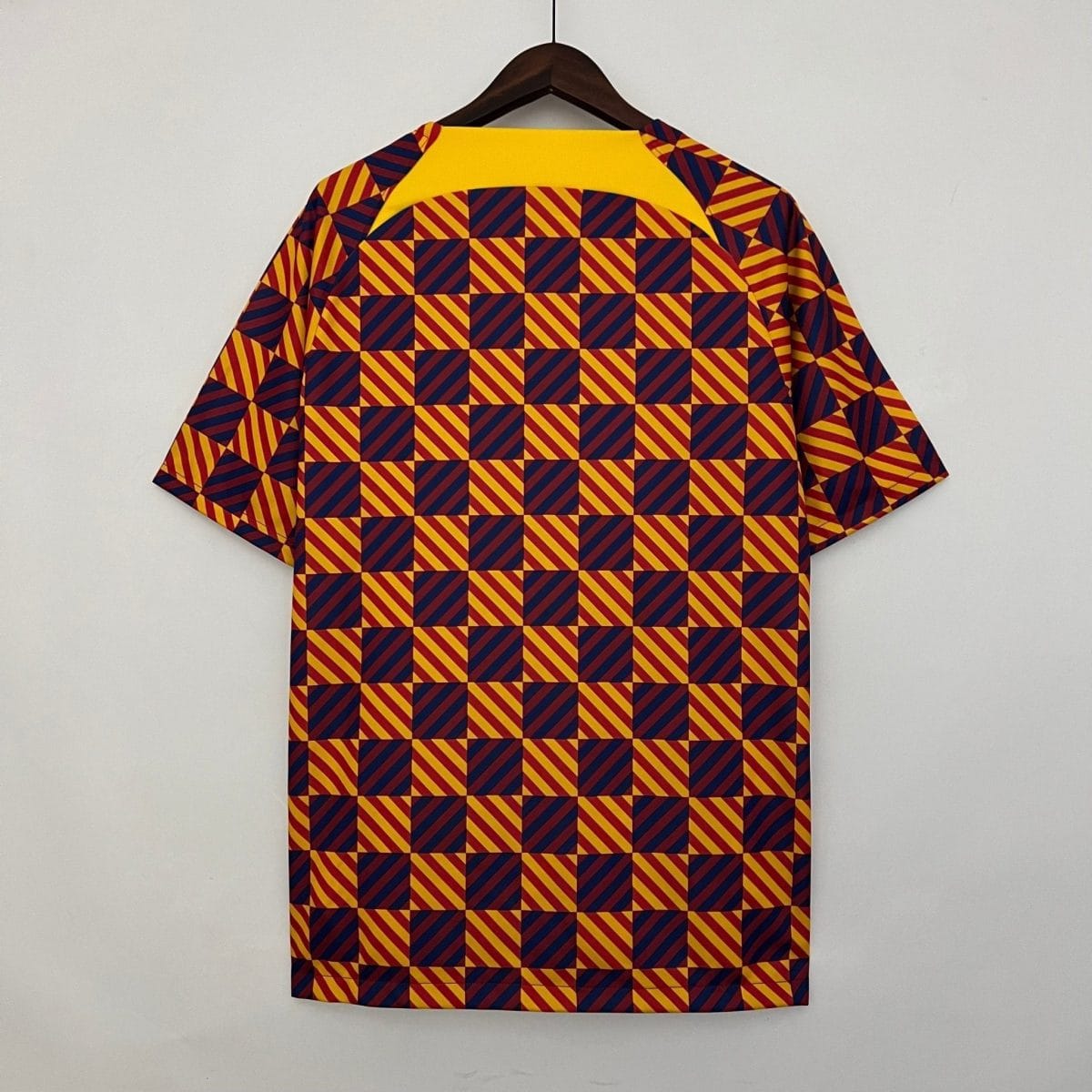 Shirt on a hanger with a bold yellow collar and a repeating navy-and-yellow diagonal checker pattern on red background.