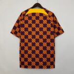Shirt on a hanger with a bold yellow collar and a repeating navy-and-yellow diagonal checker pattern on red background.