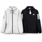 Pair of Adidas windbreaker jackets in white and black, each with a hood, zip front, and rainbow striped sleeves with logos.