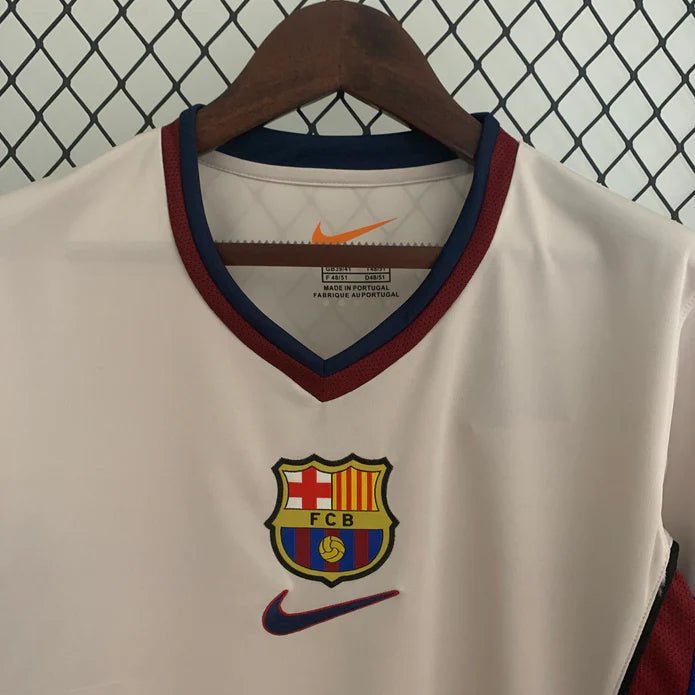 rn-image_picker_lib_temp_e1921803-a89a-41b9-8161-f6842d32c291 | UAE SPORT STORE White FC Barcelona soccer jersey on a hanger, featuring a burgundy-and-navy V-neck, orange Nike swoosh, and the club crest on the chest.