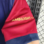 rn-image_picker_lib_temp_e2b5901d-09e3-46b1-b7e1-a5eae79299d0 | UAE SPORT STORE Red sleeve with yellow AMBILIGHT tv logo on a navy cuff against a metal rack background