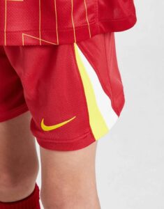 rn-image_picker_lib_temp_e61ff3fc-feb3-4977-9063-2f714e2fd4d5 | UAE SPORT STORE Red athletic shorts with yellow side stripe and a yellow Nike swoosh logo on the leg.