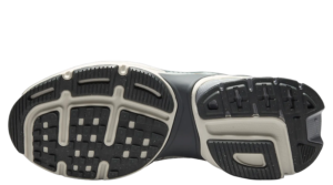 Bottom view of a dark athletic shoe with a textured tread pattern and white accents on the sole for traction.