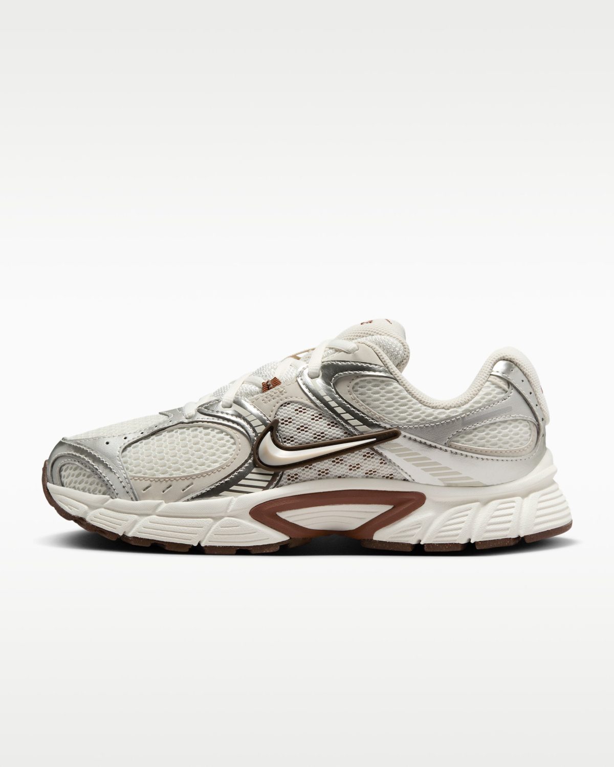 White and gray athletic sneaker with a brown Nike swoosh, shown from the side with a chunky sole and breathable mesh panels.