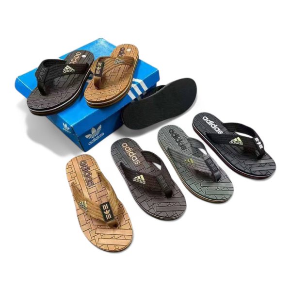 Assorted Adidas flip-flops in black, brown, and gray arranged on a blue shoebox with the brand logo visible