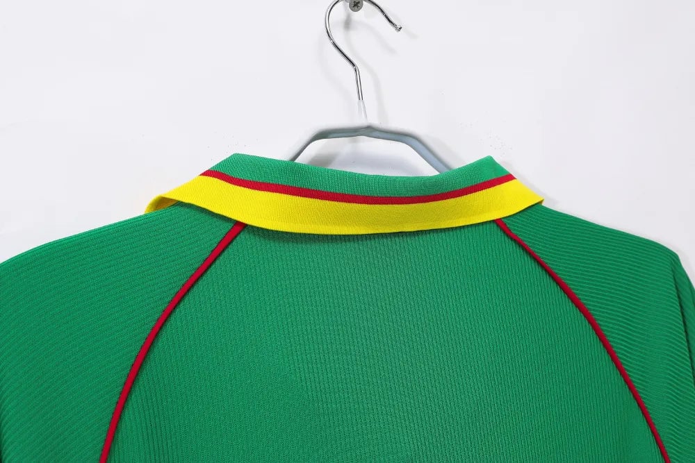 rn-image_picker_lib_temp_eb1e646c-251e-4bbe-9e58-6ac1cacccfdb | UAE SPORT STORE Back view of a green polo shirt on a hanger, featuring a yellow collar with a red stripe and red piping along the seams.