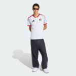 Male model wearing a white UAEFA jersey with red trim, black Adidas logo, sunglasses, and dark jeans, standing against a light background.
