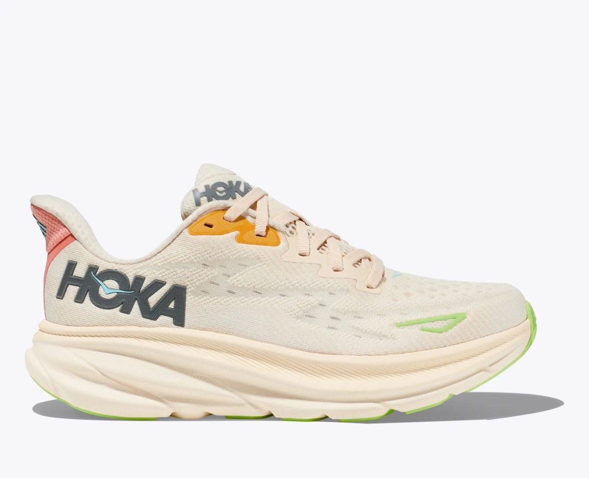 Beige Hoka running shoe shown from the side with pink tongue and lime-green sole details.