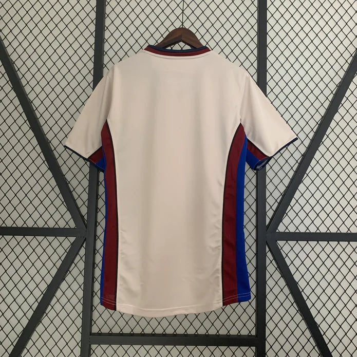 rn-image_picker_lib_temp_ed9d92c4-8f33-45e7-94e2-f80c94fe38f9 | UAE SPORT STORE Back of a cream soccer jersey with red and blue side panels hanging on a rack.
