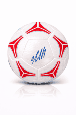 White soccer ball with red and blue decorative panels and a blue cursive signature, shown with reflection beneath.