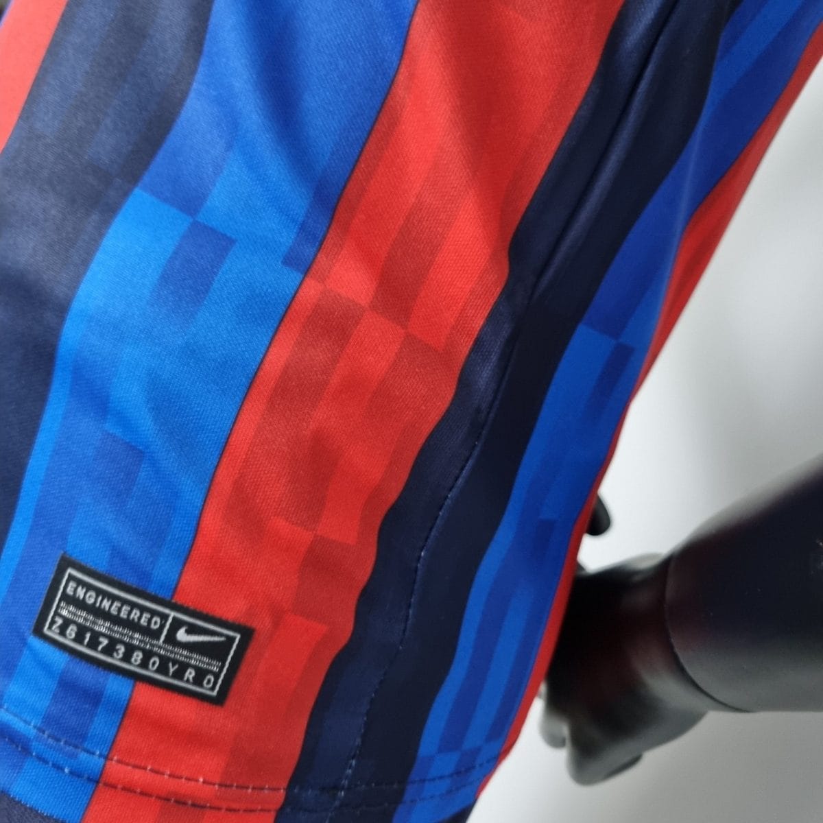 Close-up of red and blue striped fabric with a black label reading 'ENGINEERED'.