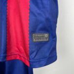 Close-up of blue fabric with a red wavy seam running vertically, and a small black label reading 'ENGINEERED' with numbers underneath.