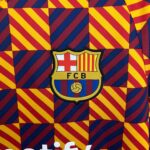 FC Barcelona crest on a colorful diagonal striped background (red, yellow, and blue).
