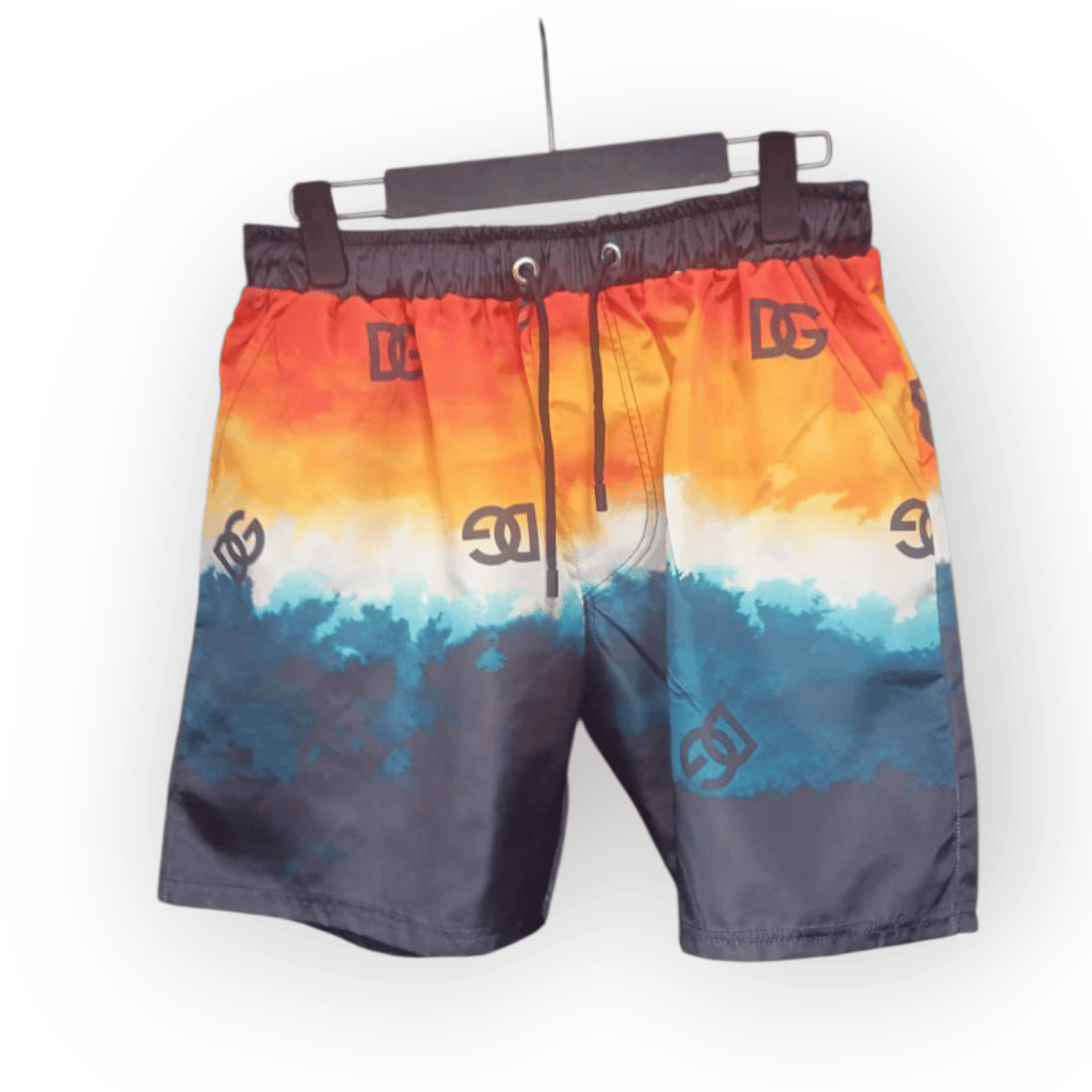Colorful gradient swim shorts hanging on a black hanger with DC logos visible on the fabric.