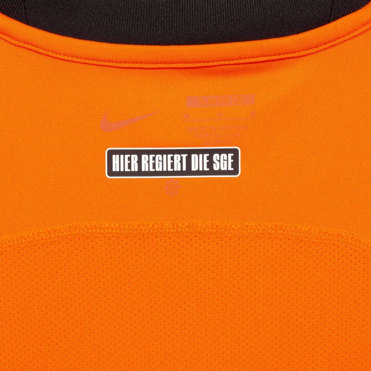 Orange sports jersey with a black-bordered white badge reading 'HIER REGIERT DIE SGE' on the chest area.
