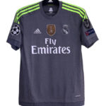 Dark gray Real Madrid football jersey with neon green shoulder stripes, Fly Emirates sponsor, and Champions League badge on sleeve (front view).