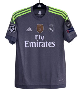Dark gray Real Madrid football jersey with neon green shoulder stripes, Fly Emirates sponsor, and Champions League badge on sleeve (front view).
