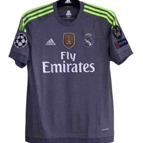 Dark gray Real Madrid football jersey with neon green shoulder stripes, Fly Emirates sponsor, and Champions League badge on sleeve (front view).