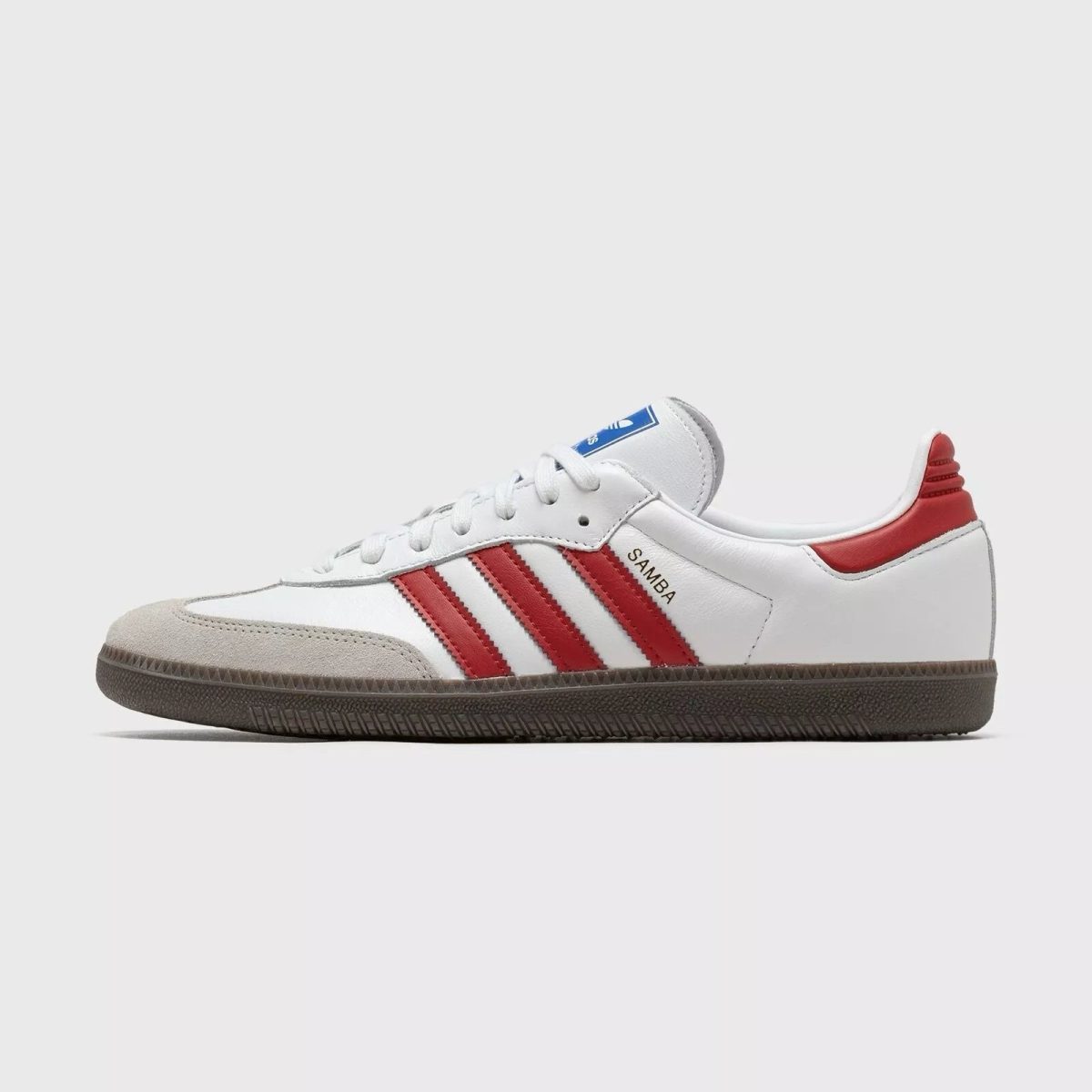White Adidas Samba sneaker shown in a side profile with red stripes and a brown gum sole.