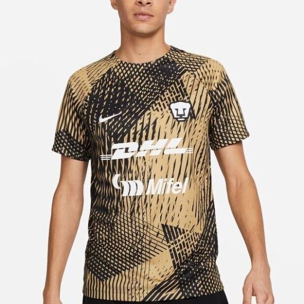 Male model wearing a tan and black geometric-patterned soccer jersey with sponsor logos DHL and Mifel and a Nike swoosh on the chest.