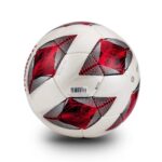 Close-up of a white soccer ball with red and black patterned panels and visible stitching against a white background.