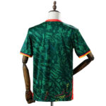 Back view of a green athletic jersey with an abstract lime-green pattern and red/yellow trim on the sleeves, displayed on a dress form.