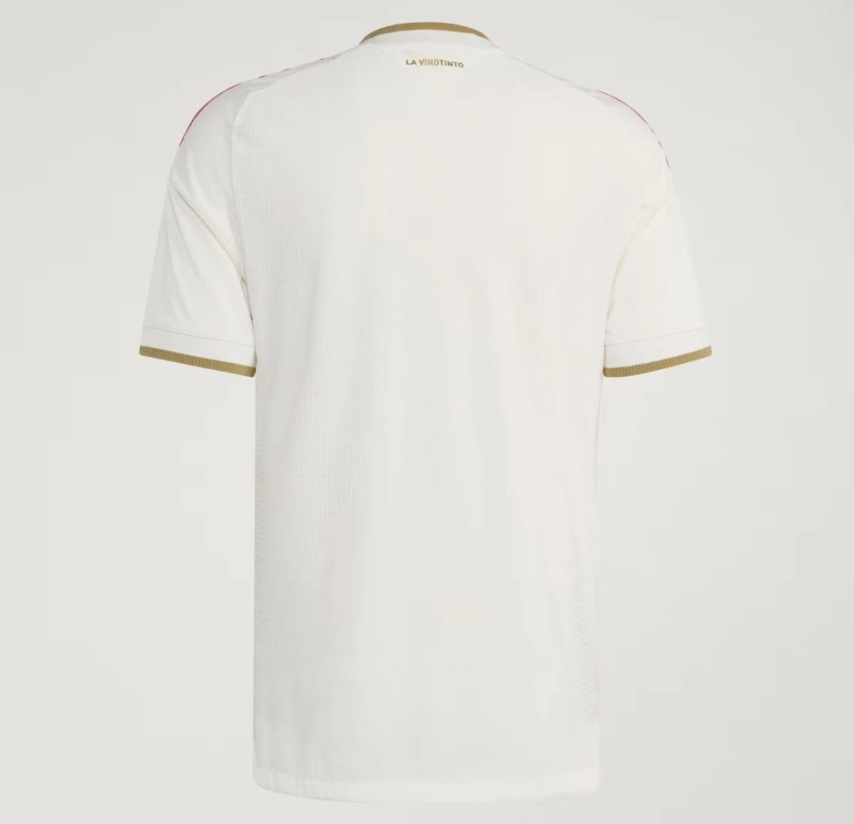 Back view of a white T-shirt with gold trim on the sleeve cuffs and neckline, LA VINOTINTO at the neck.