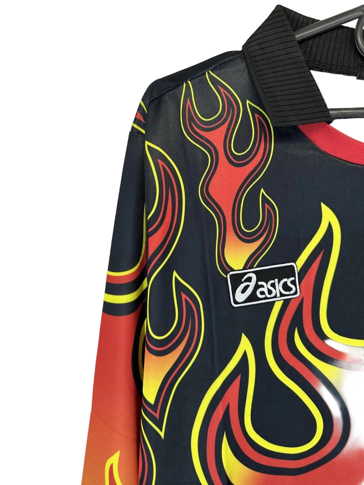 s-l1600_2_6c08bfe8-cc0d-42ff-95d4-277e053c4883 | UAE SPORT STORE Close-up of a dark athletic shirt with bright yellow and red flame patterns and an Asics logo, hanging on a black hanger.
