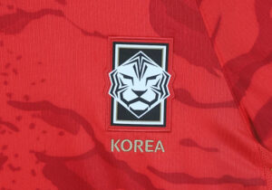 Close-up of a red sports jersey crest featuring a white tiger emblem and the word KOREA underneath.