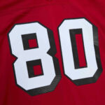 Red sports jersey with large white number 80 outlined in black on fabric surface.