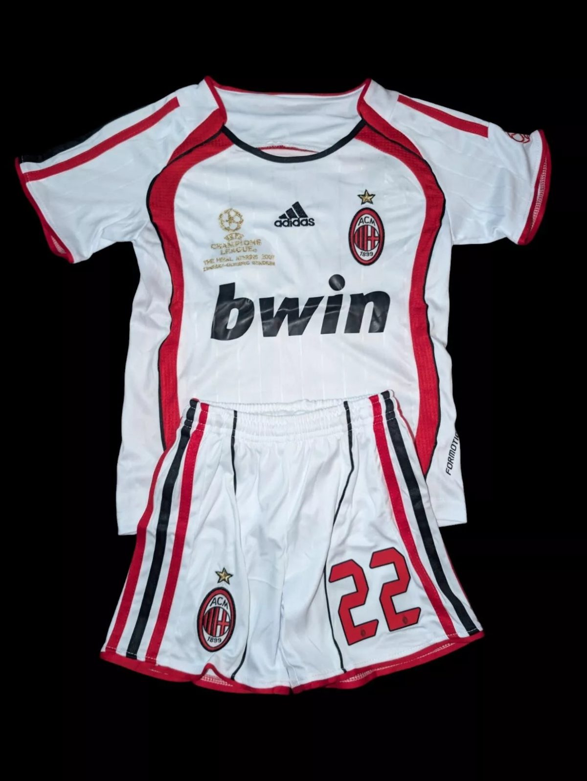 AC Milan white home kit laid flat: crest with star, black Adidas logo, gold Champions League patch, bwin sponsor, red trim, and matching shorts with number 22.