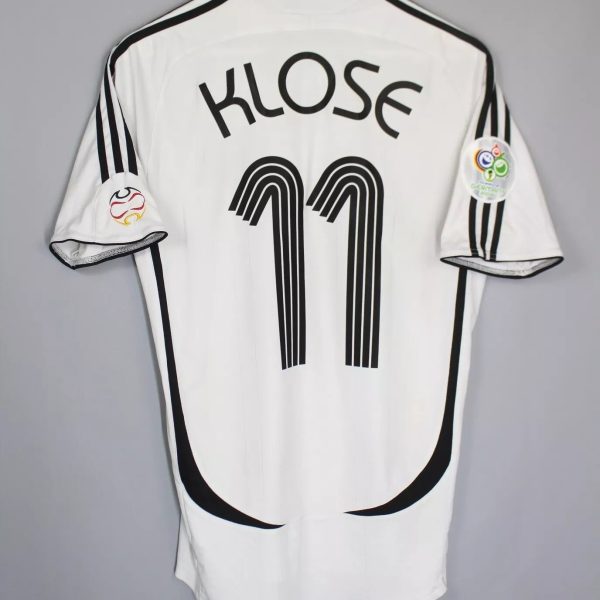 White soccer jersey with 'KLOSE' and the number 11 on the back, black trim along shoulders, hanging on a hanger.
