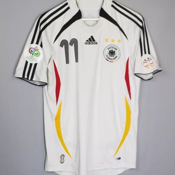 White Germany national football jersey on a hanger, with black Adidas stripes, number 11, crest and three gold stars on the chest.