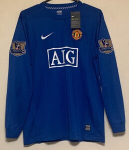 Blue Manchester United soccer jersey with AIG sponsor logo and Barclays patches on sleeves, Nike swoosh, tag on chest.