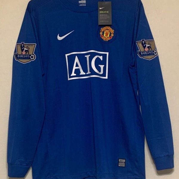 Blue Manchester United soccer jersey with AIG sponsor logo and Barclays patches on sleeves, Nike swoosh, tag on chest.