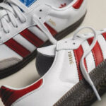 White Adidas Samba sneakers with red stripes, close-up of side panel and laces.