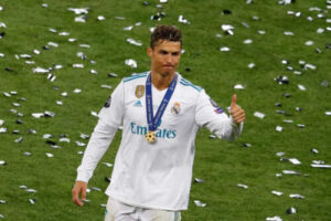 s-l500_20_7adb2baa-ff18-436a-8e80-1c1e61f9378c | UAE SPORT STORE Cristiano Ronaldo in Real Madrid kit with medals around his neck giving a thumbs up on a confetti-covered pitch.