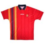 Red Adidas Spain soccer jersey featuring a yellow diamond pattern on the left panel, with a crest on the chest and a dark collar.