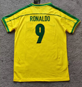 s-l960_10 | UAE SPORT STORE Yellow Brazil national team soccer jersey laid flat, back shows name RONALDO and number 9 in green.
