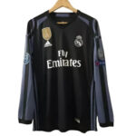 s-l960_24de9438-59af-4a28-b3ba-d86fbfc752b8 | UAE SPORT STORE Black Real Madrid jersey on a hanger with Fly Emirates sponsor and team crest visible, long sleeves with blue-gray stripes.