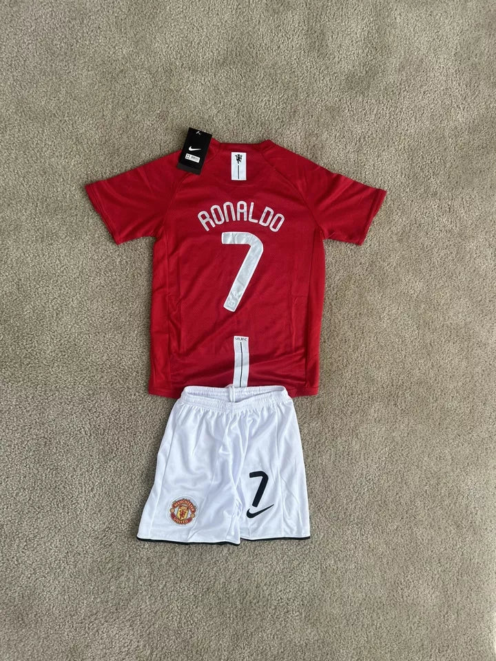 s-l960_6 | UAE SPORT STORE Red Ronaldo #7 football jersey laid on beige carpet with white Manchester United shorts showing the number 7 and club crest nearby.